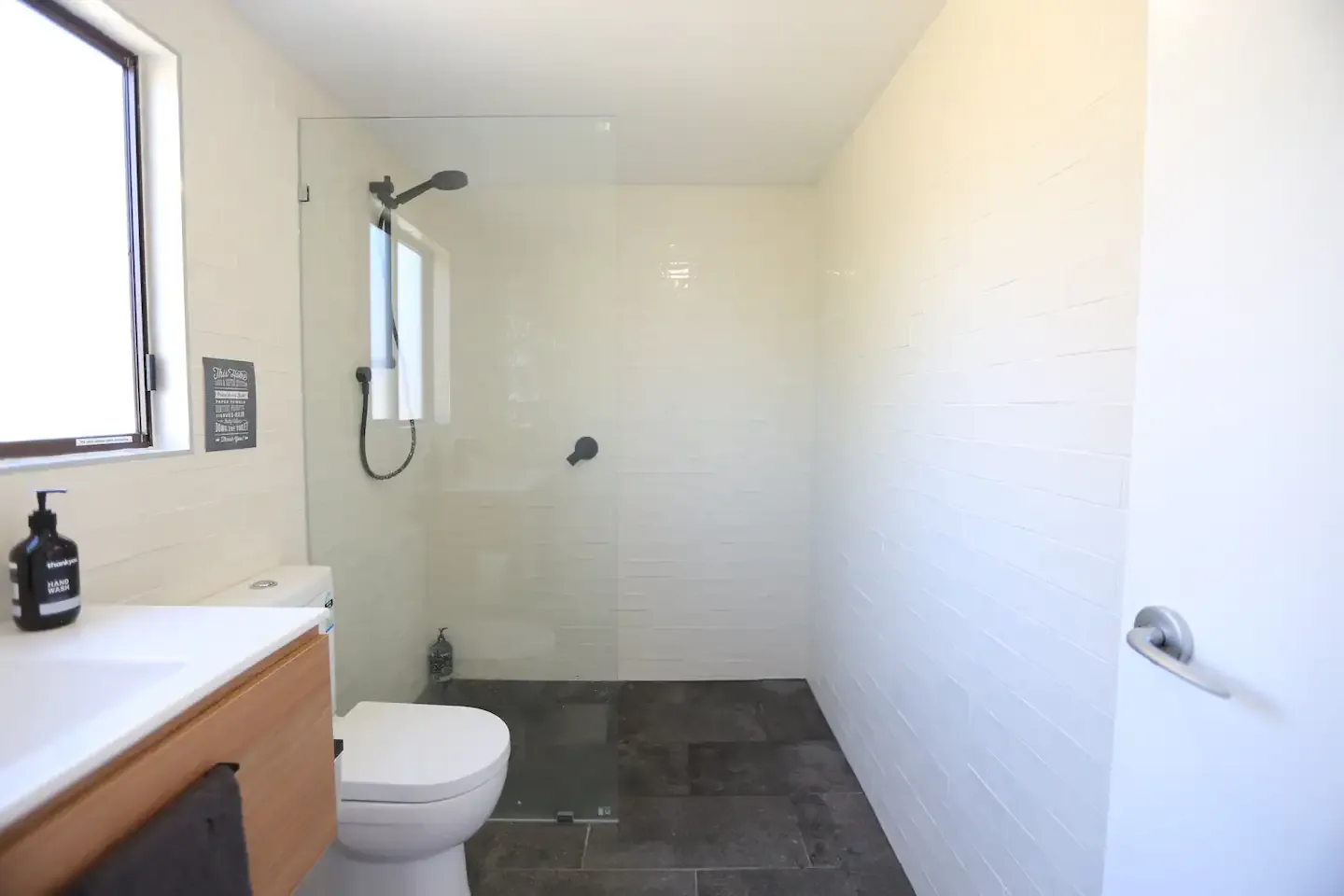 Small renovated toilet and shower area with a glass screen