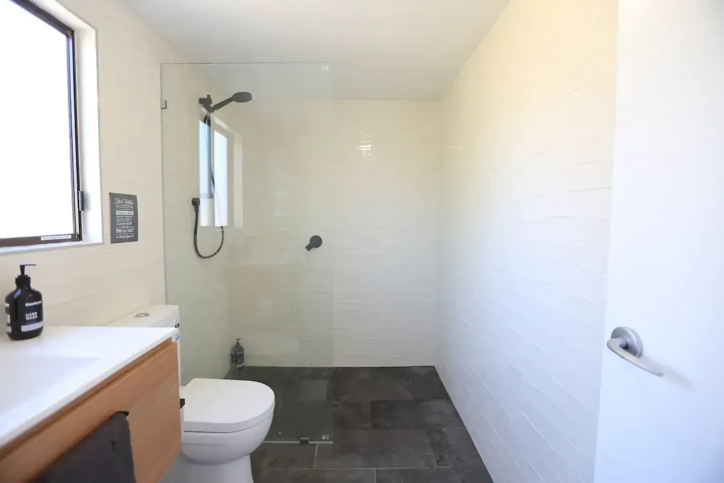 Small renovated toilet and shower area with a glass screen