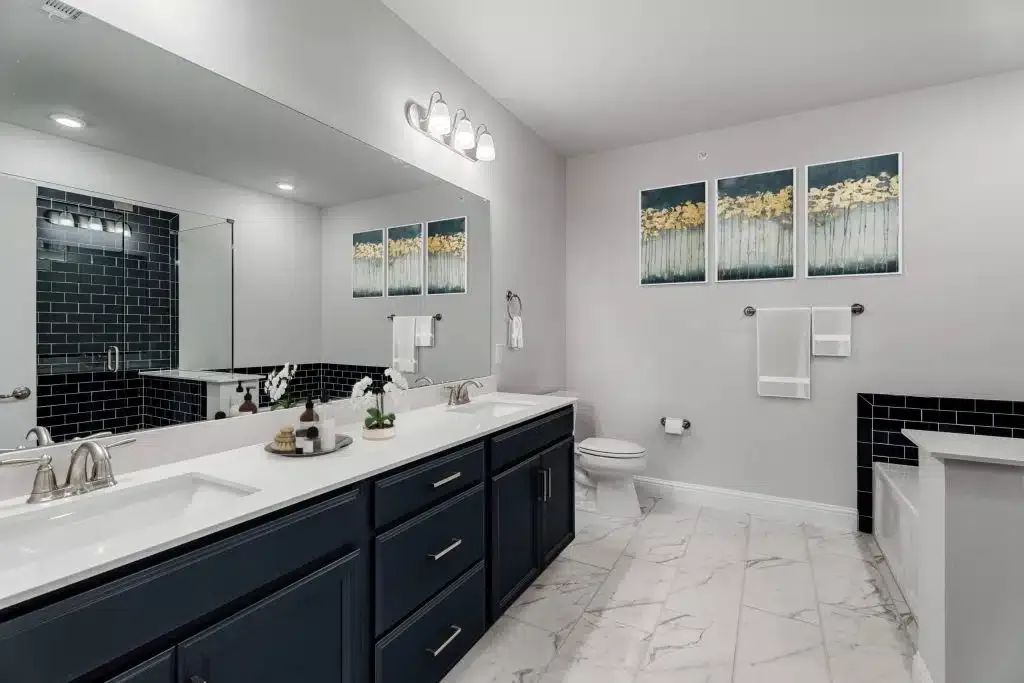 Navy vanity bathroom with double sink, black subway-tile shower and framed artwork