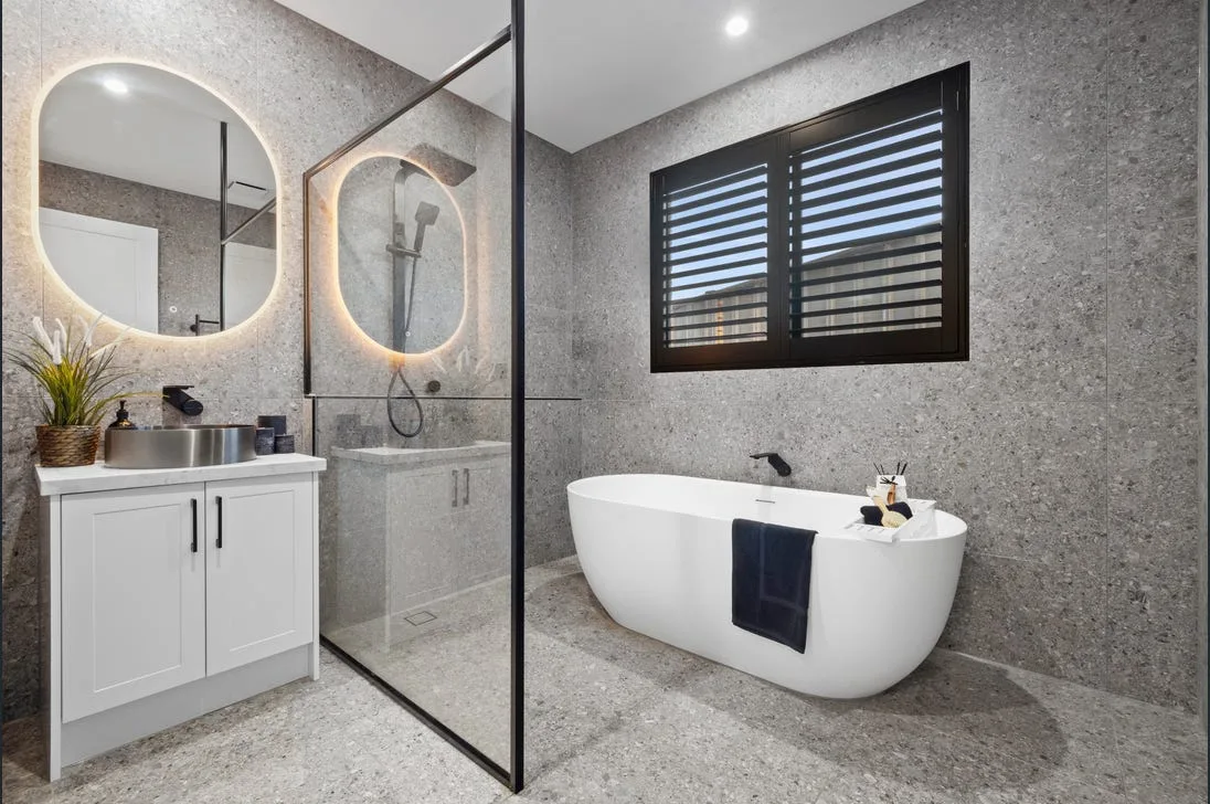 Terrazzo-look bathroom with an oval freestanding tub and dual round backlit mirrors
