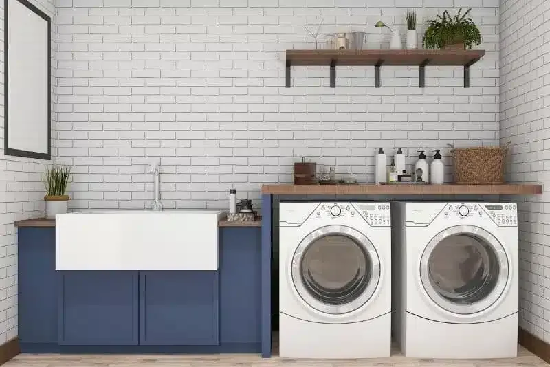 Navy laundry cabinetry with a built-in sink beside a front-loading washer and dryer
