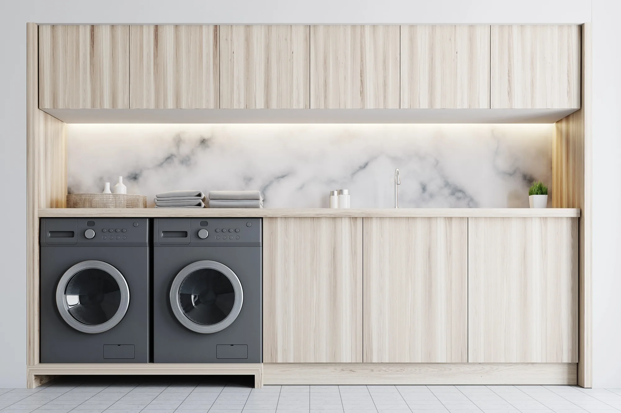 Twin front-loading washer and dryer built into a timber cabinet with a marble splashback